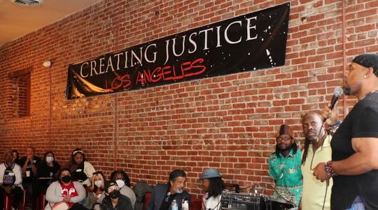 Kayo from Creating Justice LA speaking to people on stage