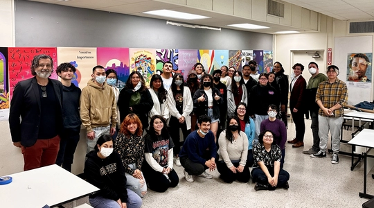 A classroom at Cal State Los Angeles with dozens of students smiling in front of artwork.