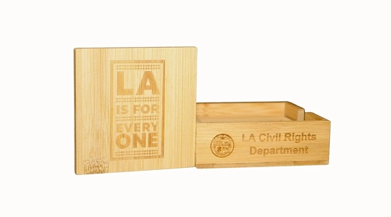 A square, light bamboo coaster set in a holder. The top coaster is engraved with "LA IS FOR EVERY ONE" and the holder is engraved with "LA Civil Rights Department."