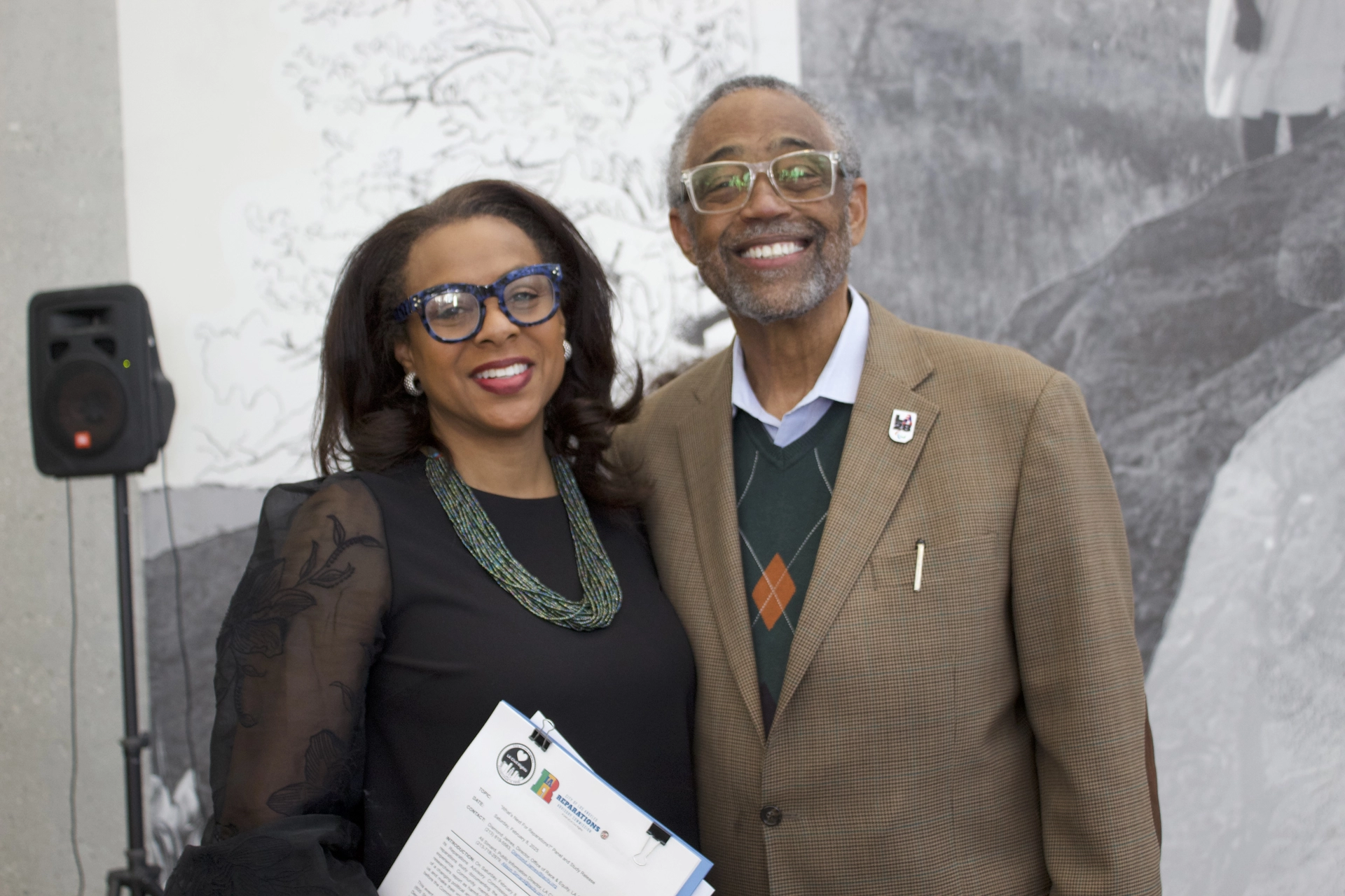 Capri poses with someone at the reveal of the Reparations Report.