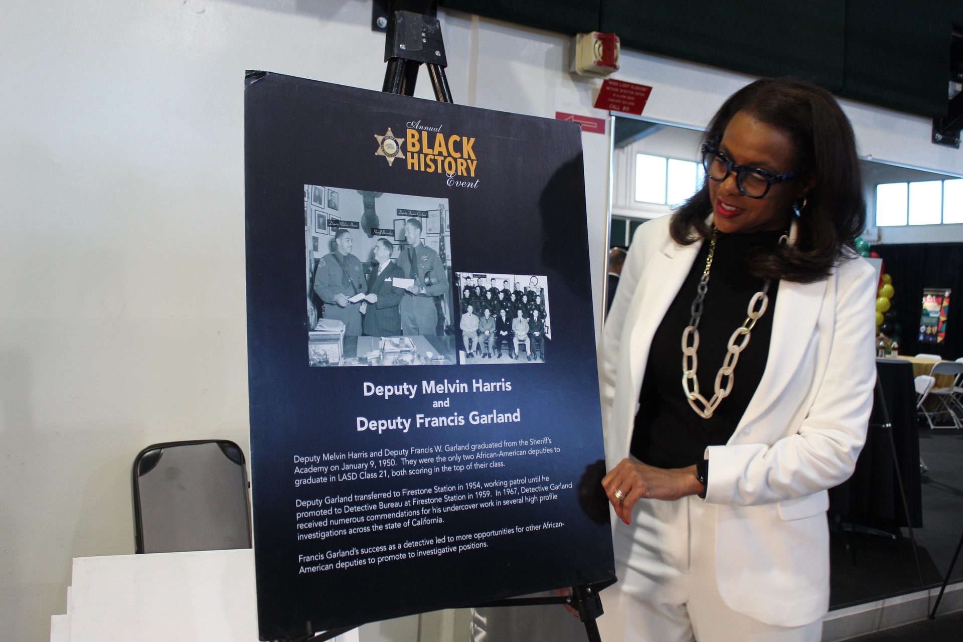 E.D. Capri Maddox looking at the annual Black History Month event poster honoring Deputy Melvin Harris and Deputy Francis Garland.