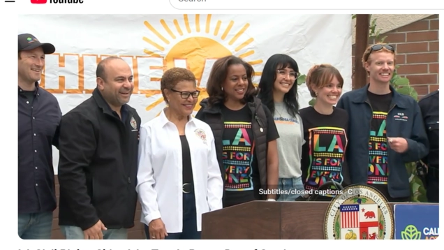 A group including Josh Fryday from the Governor’s Office, LA City Councilmember Adrin Nazarian, LA Mayor Karen Bass, LA Civil Rights Executive Director Capri Maddox, and members of the Tom LaBonge family stand smiling together in front of a Shine LA banner and a City of Los Angeles podium during the Tom LaBonge Day of Service event.