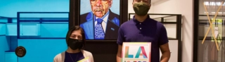 two people in front of John Lewis painting holding LA For All posters