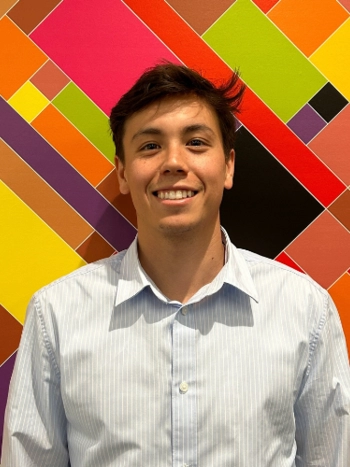 Kenny Racs smiles and stands in front of a mosaic wall at LA Civil Rights Department