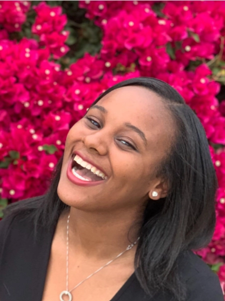 Jamila Cummings smiling with pink flowers as background