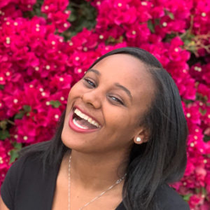 Jamila Cummings smiling with pink flowers as background