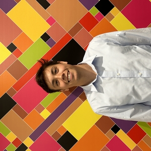 Kenny Racs smiles and stands in front of a mosaic wall at LA Civil Rights Department